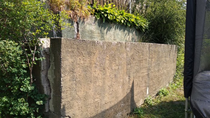 En gammal mur byggd i tre steg utan armering med synliga sprickor och omgiven av växtlighet.