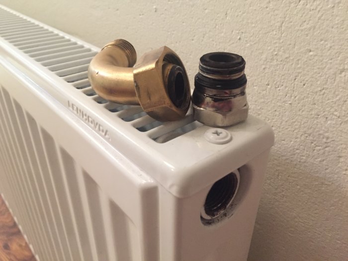 Närbild på radiator med kopplingar och ventiler för VVS-installation.