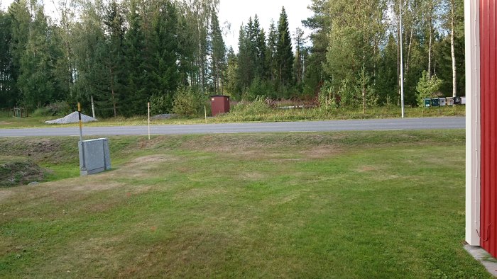 Vy över en gräsmatta med väg, elskåp och brevlådor i bakgrunden som visar avstånd för eldragning.