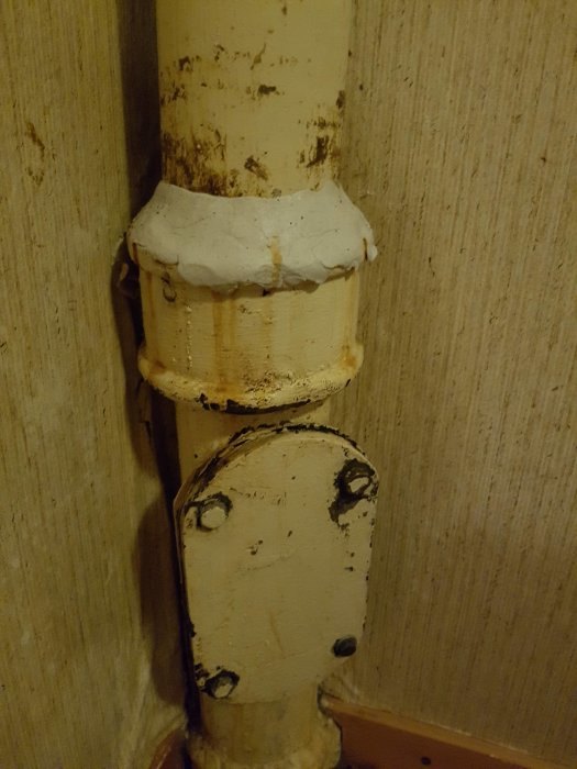 Avloppsrör täckt med vit rörkitt mot läckage vid skarv, monterade på vägg.