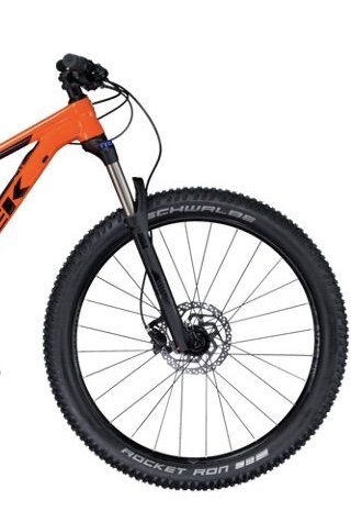 Framdel av en orange mountainbike (MTB) med fokus på det framskjutna hjulet och gaffeln.