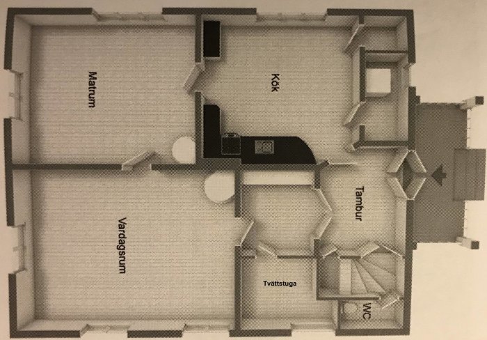 Svartvit planritning av ett hus med kök, vardagsrum, tvättstuga, WC och trapphus markerade.