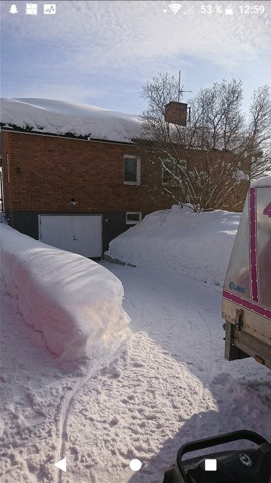 Ett hus med snötäckt tak och takrännor, synliga men inte överväldigande isbildningar.
