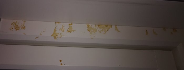 Fläckar på vitmålad tröskel, skador och färg som flagar bort.
