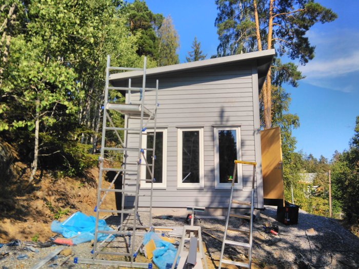 Hus under renovering med vindskiveplåt vid nock på taket, och byggställning runtom.