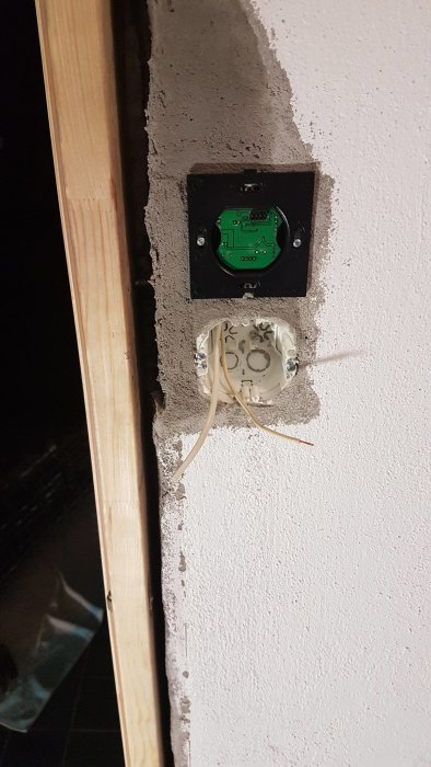 Installation av eluttag med öppen kabel och monteringsdosa i vägg under renovering.