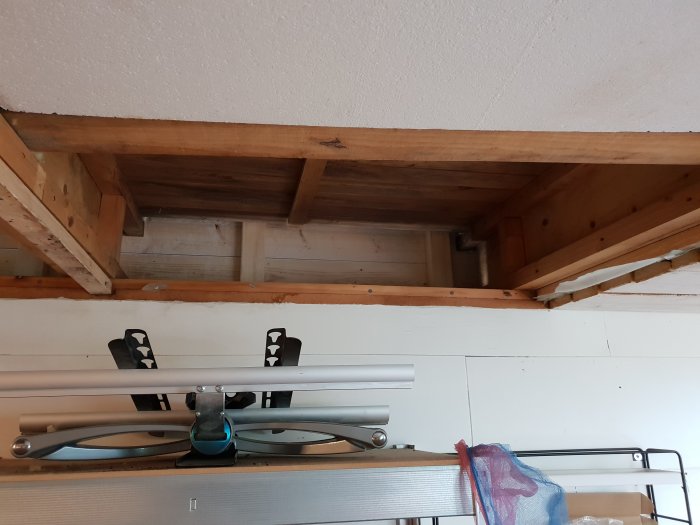 Öppen träkonstruktion i garagets anslutning till huset med insida av ytterpanel synlig.