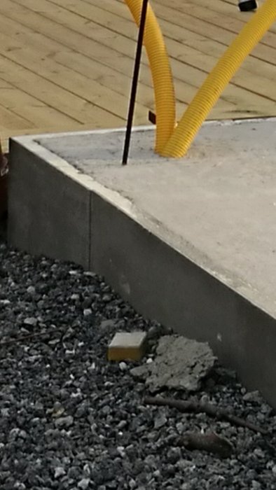 Betongplatta för garage med synlig cellplast i kanten och grus runtomkring.