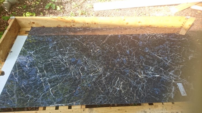 Granitkeramikplatta med marmorimitation av typen Saint Laurent, storlek 2,4x1,2m, reflektion av blå himmel synlig.