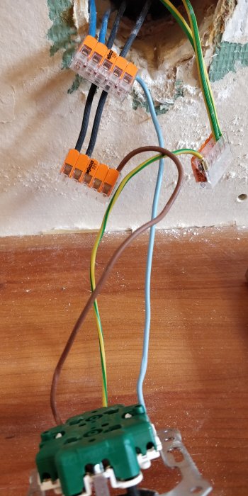 Installation av Exxact uttag med synliga plintar och elledningar mot en vägg.