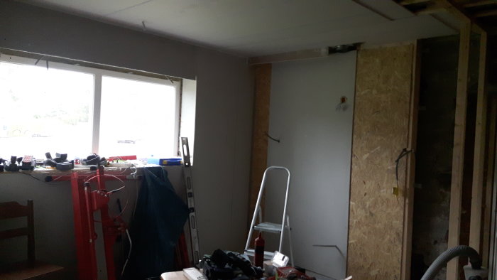 Omfattande renovering i kök med dubbelgips i taket och pågående gipssättning på väggar, verktyg synliga.