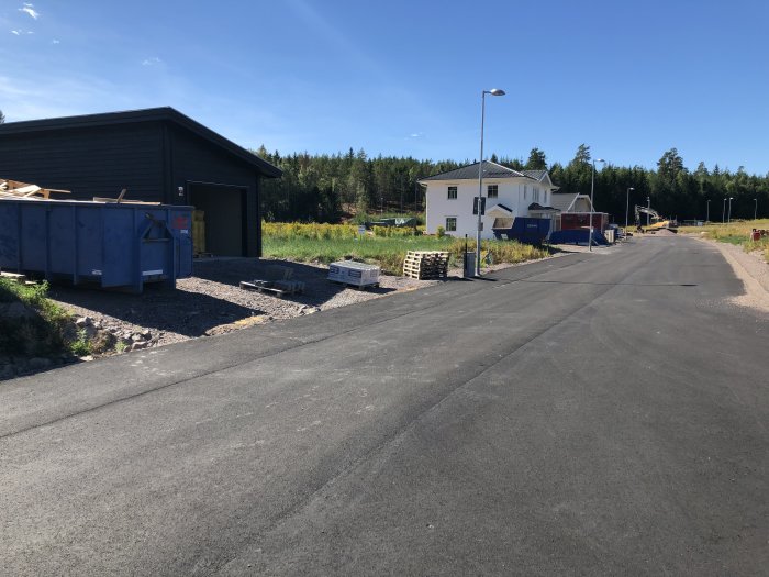 Nybyggda hus och pågående byggarbete längs en asfalterad gata i ett bostadsområde.