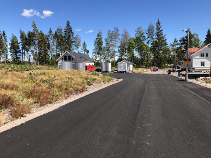 Nybyggt bostadsområde med väg och nyligen uppförda hus omgivna av skog.