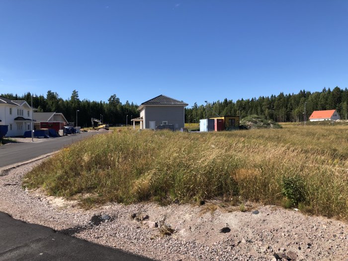 Nybyggnadsområde med några hus och pågående byggarbeten under en klarblå himmel.