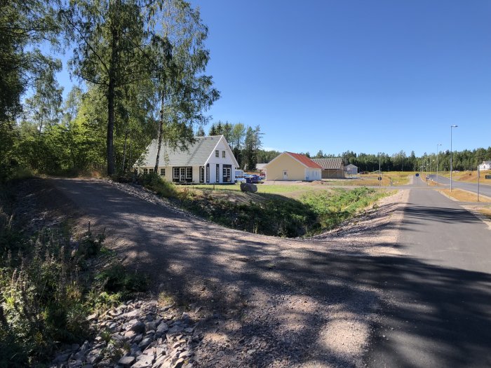 Nybyggt bostadsområde med flera hus och anlagda gator i soligt väder.