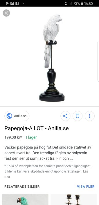 Vit papegoja-skulptur på svart, hög träfot, som inredningsdetalj.