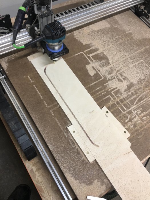 CNC-maskin skär ut delar till datorbord från björkplywood, liknande Ron Paulks design.