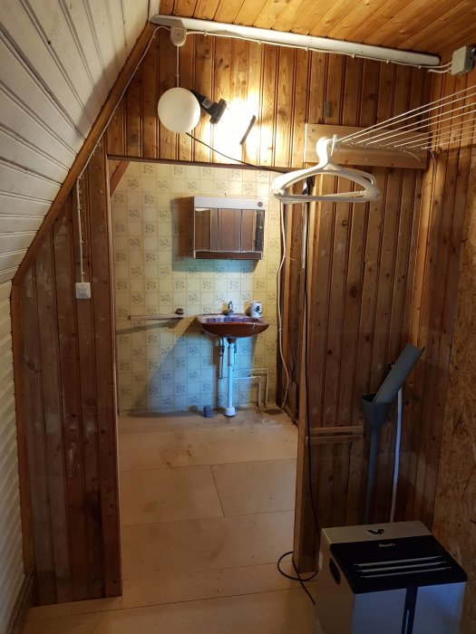 Tömmande av ett torkrum med gammal handfat och radiator, förberett för renovering till badrum.