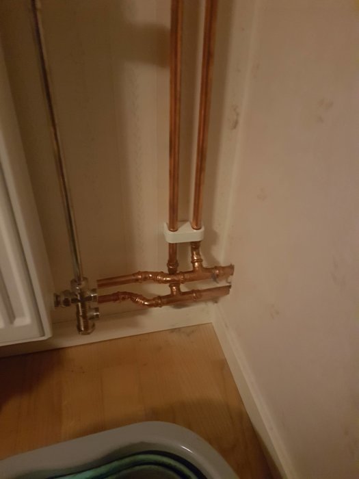 Kopparledningar vid en vägg som ansluter till ett element, med T-koppling och böjar.