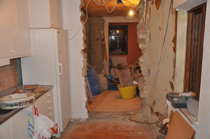 Inomhusrenovering med tegelstommen synlig, röran och riven vägg i en köksmiljö.
