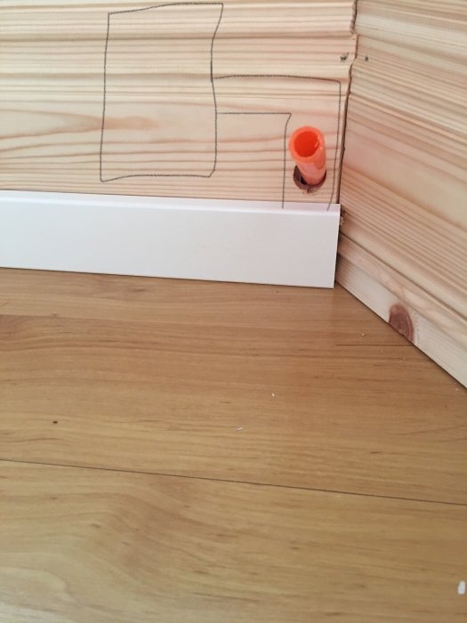 Hörnet av ett rum med markerad yta på vägg för kabelränna och synlig orange rörända.