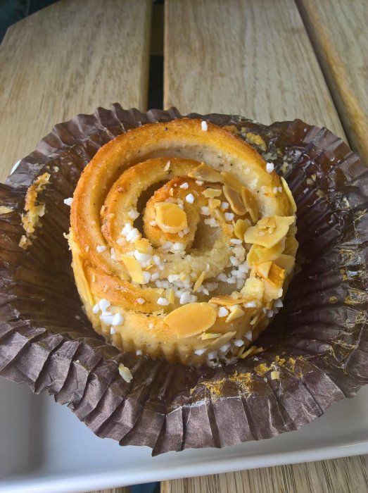 Sockerkaka med mandel och pärlsocker på träbord, delvis uppäten.