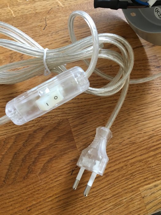 Elsladd med strömbrytare och stickkontakt på ett trägolv.