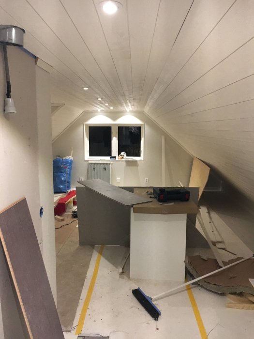 Renovering av hyresrätt över garage med ljusgrå gipsskivor, inbyggda spottar och omonterat kök.