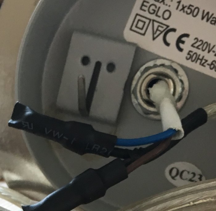 Närbild av ett lampmonteringsområde med anslutna kablar och fästklem.