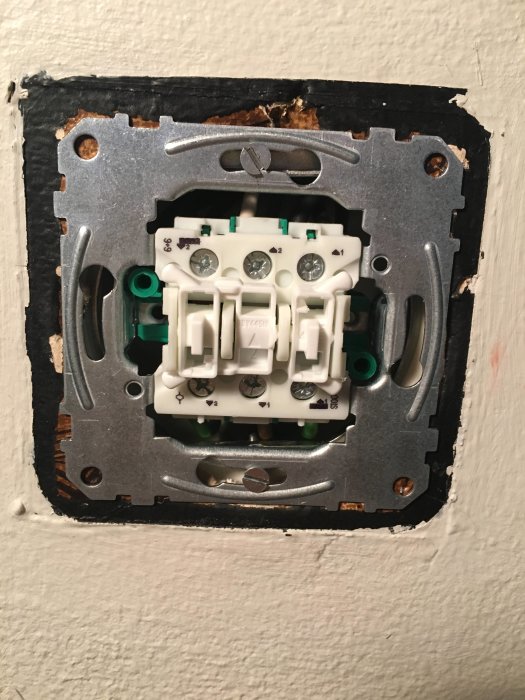 Nytt vägguttag installerat i vägg, kablar anslutna och utan frontplatta.