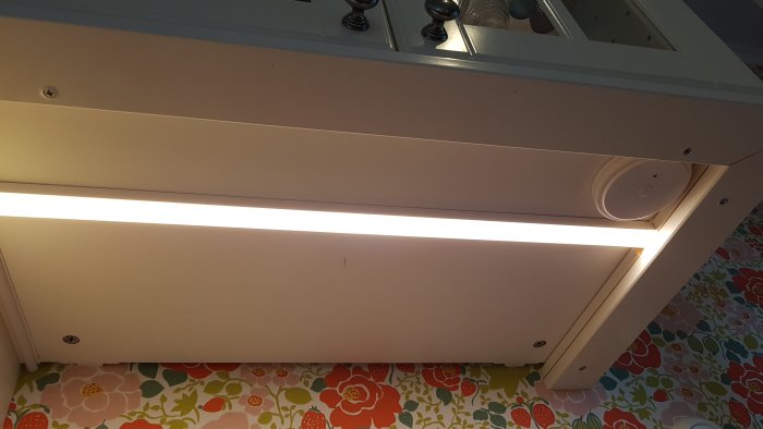 IKEA Omlopp belysning under överskåp med synlig rund fjärrkontroll och färgglad tapet.