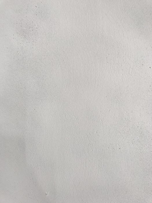 Närbild på en nymålad vägg med synliga slipmärken och porer efter bredspackling.