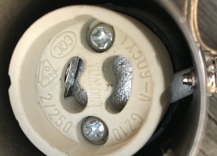 Närbild av en lamphållare med teknisk information och anslutna dubbelisolerade sladdar.