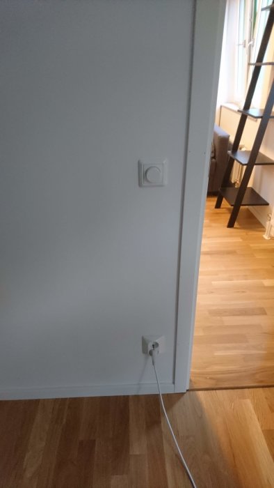 Dimmer och eluttag i en vägg i ett rum, med en stege i bakgrunden.