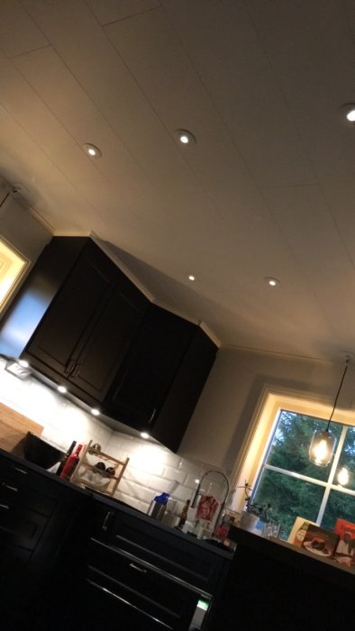 Kök med Ikeas "omlopp" belysning under överskåpen och inbyggda spotlights i taket.