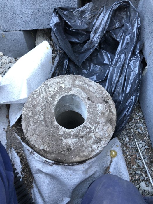 Ovanifrån bild av ett öppet betongrör i marken omgivet av gråsten och byggmaterial.