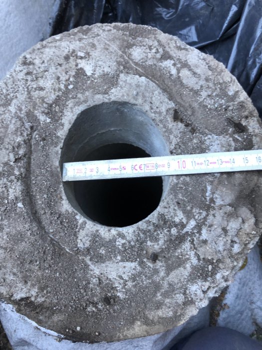 Betongrör i marken med måttband som visar rörets diameter, avsett för avloppssystem.