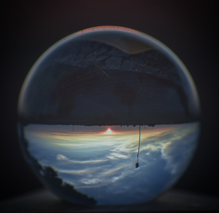 Solnedgång speglad i en kristallkula som vänder bilden upp och ned.