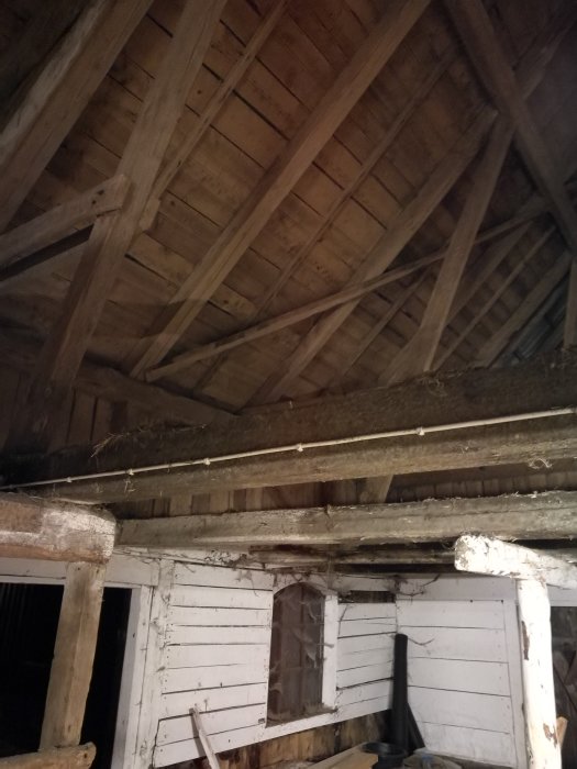 Detaljbild av ett gammalt träbjälklag och robusta takstolar i en byggnad under renovering.
