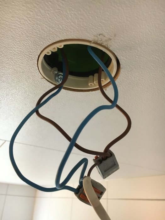 Kablage med Wago-koppling bakom en halogenspot i tak, redo för LED-konvertering.