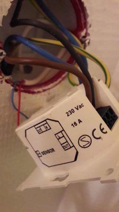 Elanslutning av termostat med svarta, blåa och bruna trådar samt märkning av in- och utgångar.