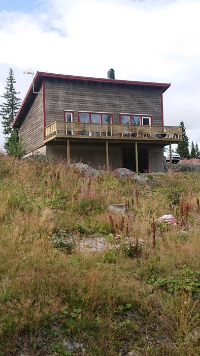 Ett tvåvåningshus med träfasad och terrass, beläget i naturlig omgivning.