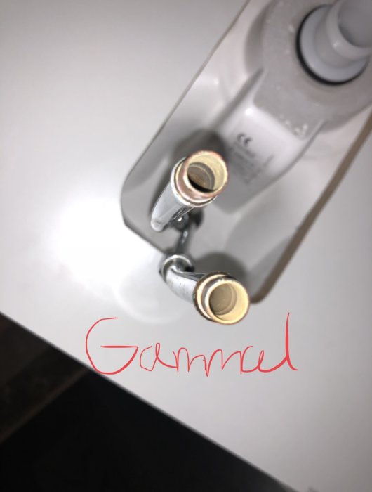 Två anslutningsrör till tvättställsblandare som inte passar ihop, med texten "Gammal" skrivet.