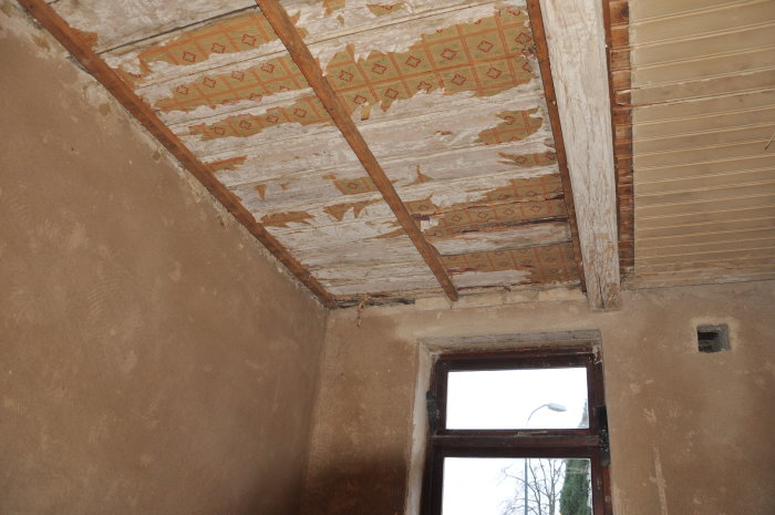 Renoverat rum med nyligen putsade väggar och ett oskadat men äldre tak med dekorativ pärlspont.