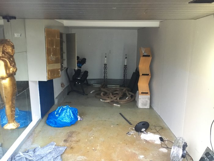 Garage i omvandling till hemmagym med träningsutrustning och borttagna skåp.