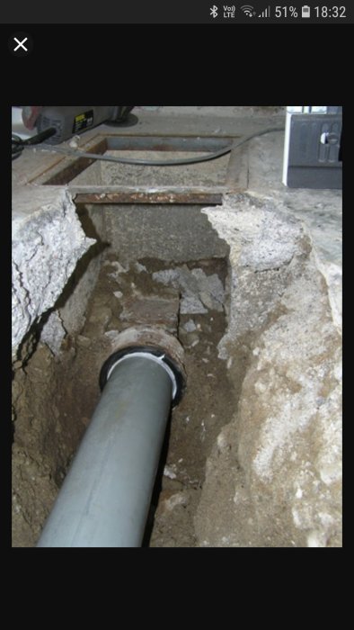 Ett gjutjärnsrör i mark med avlägsnat segment och blytätning, redo för installation av en nippel.