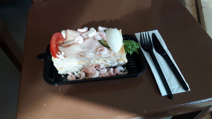 Sandwich med skinka, räkor och ägg på en byggarbetsplats lunchbord.