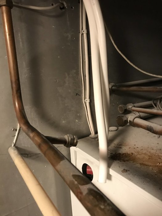 Oavslutade VVS-arbeten med osammanhängande koppar- och Prisolrör mot en vägg.
