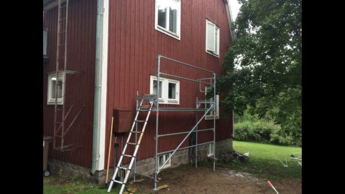 Bild på en husgavel med rött träpanel och byggställning, planer för utbyggnad längs väggen diskuteras.