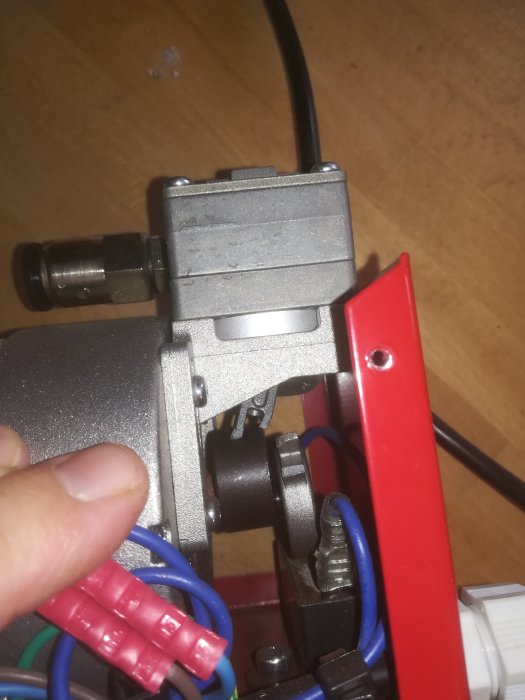 Närbild på maskindel med slitage på svart komponent och uppkopplade kablar.